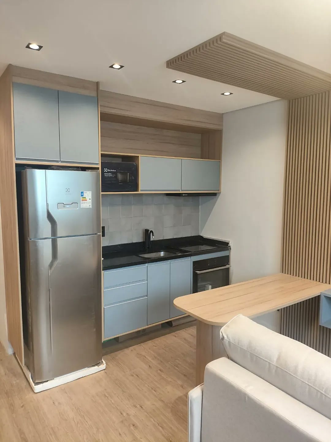 Cozinha planejada para apartamento pequeno com armários azuis, torre de geladeira e bancada americana – Estillo Design Zona Leste SP